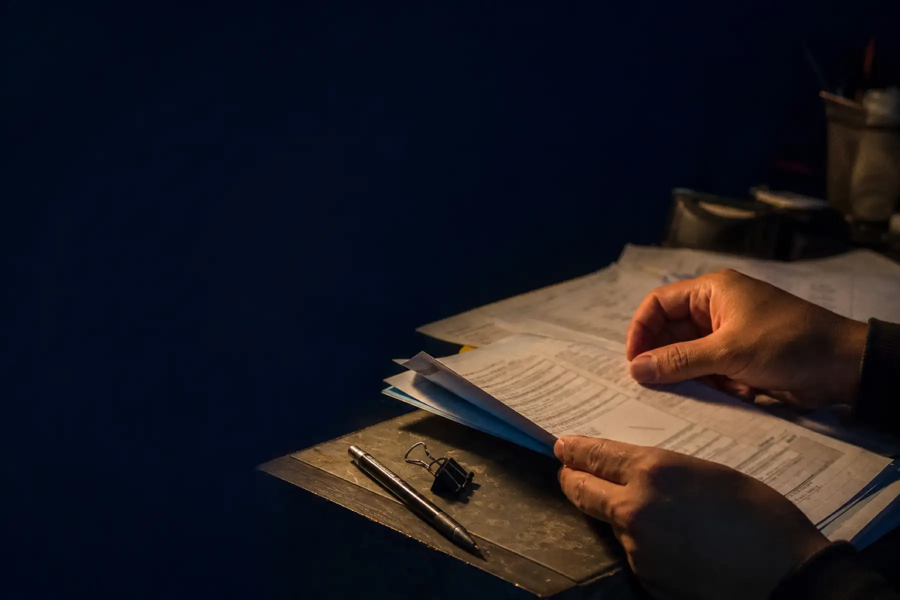 Manos revisando documentos de transporte sobre una mesa de trabajo.